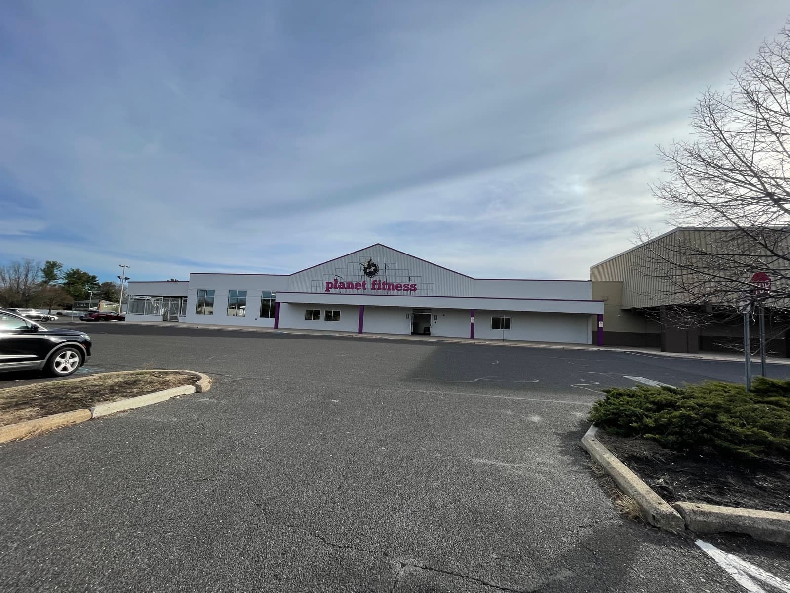 Finished gym exterior after a full repaint, bright white siding with crisp purple accents