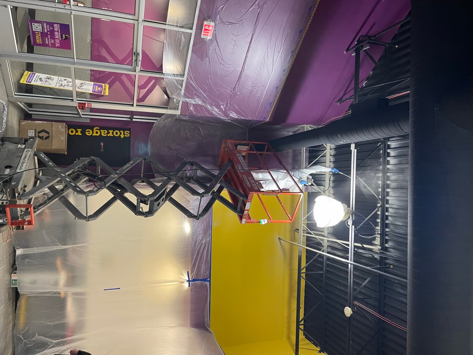 Painter spraying the ceiling of a large Philadelphia commercial interior from a scissor lift